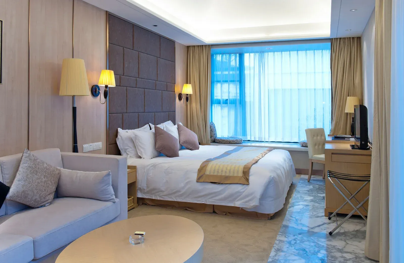 A hotel room with a king size bed , a couch , a coffee table and a television.