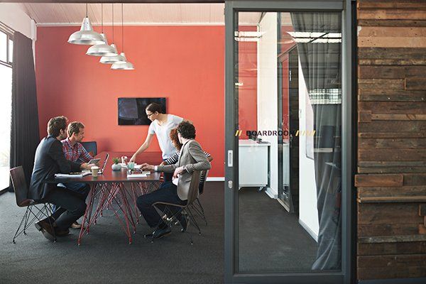 A team of five people meet in a modern boardroom.