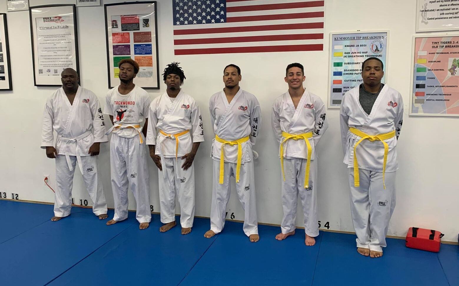 a group of men in karate uniforms stand in front of an american flag
