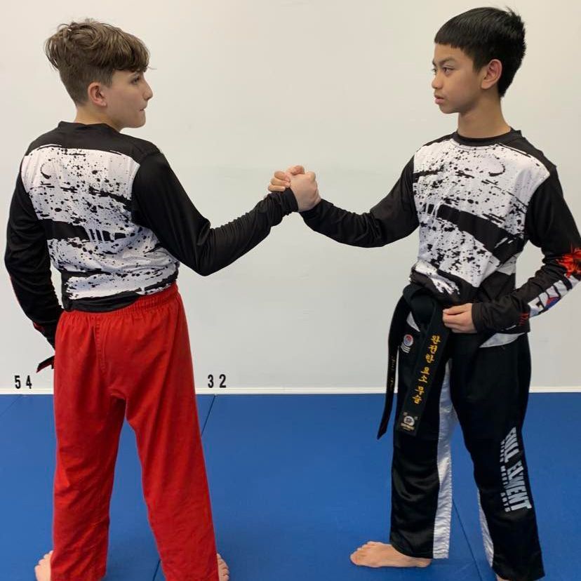 two boys wearing martial arts uniforms shake hands