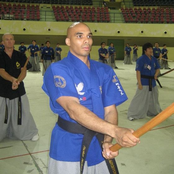 A man in a blue shirt with a black belt that says martial arts on it