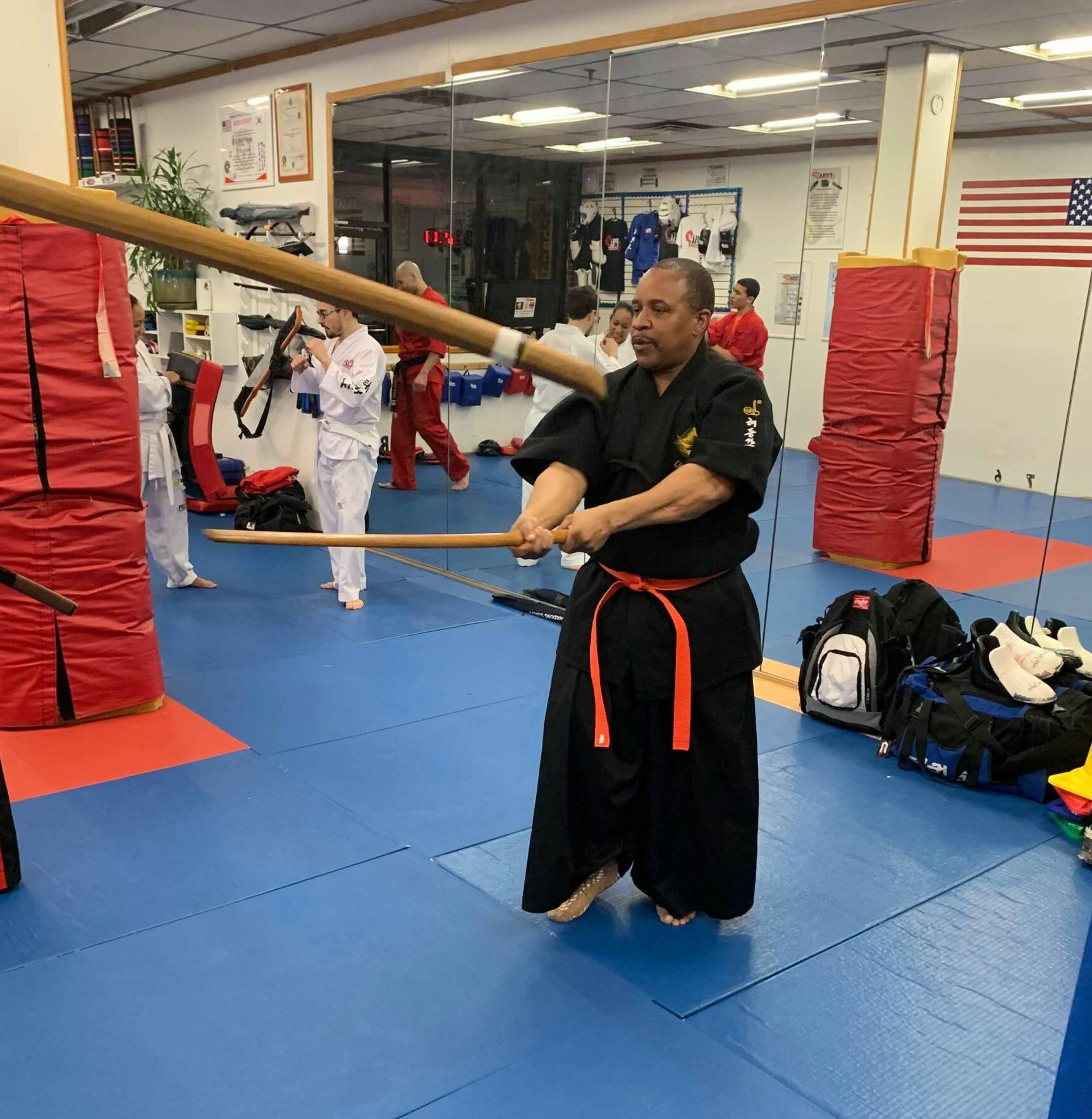 a man in a black karate uniform is holding a large wooden stick
