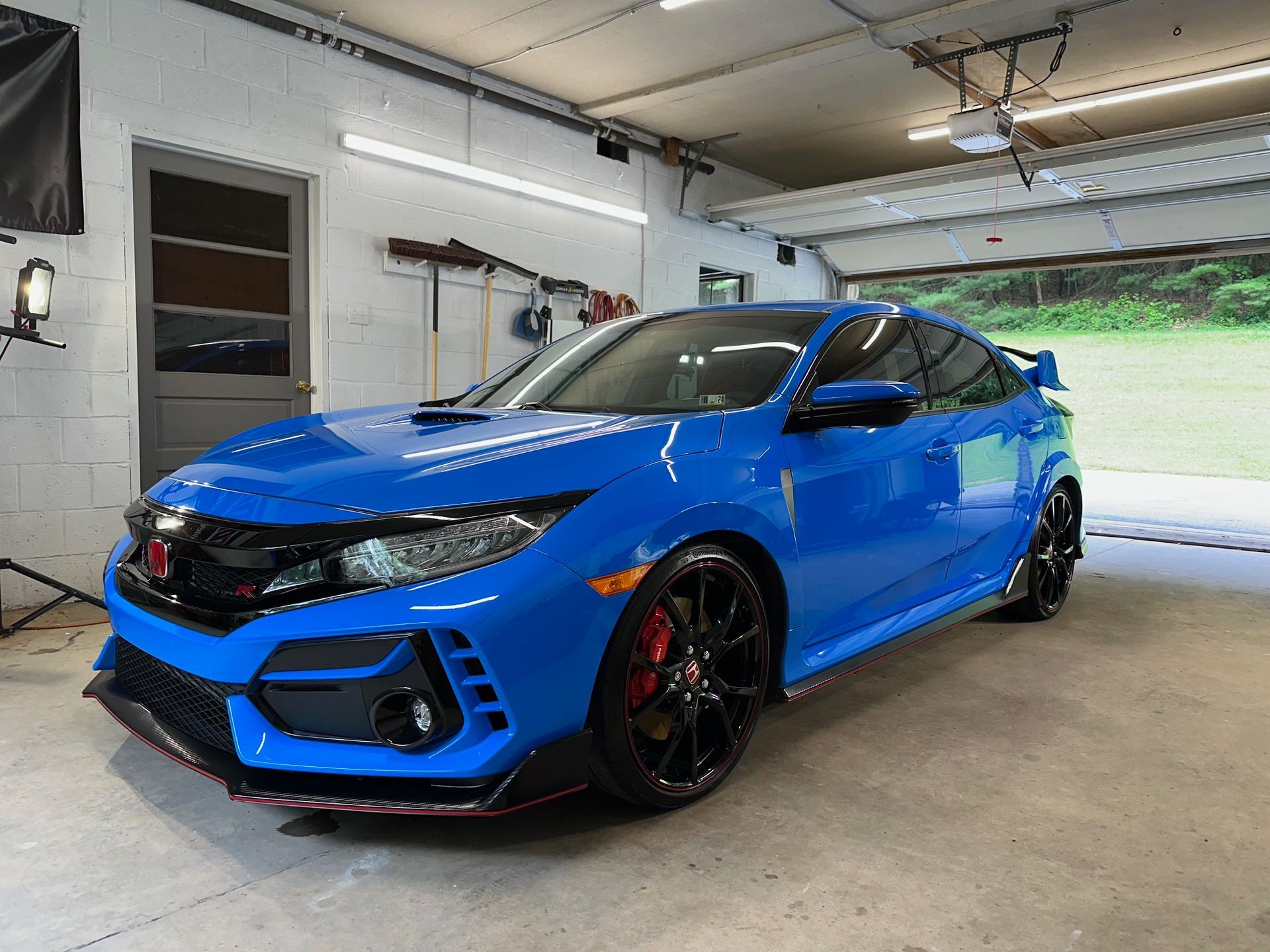 Blue Honda Civic Type R parked in a garage, with black wheels and red brake calipers.