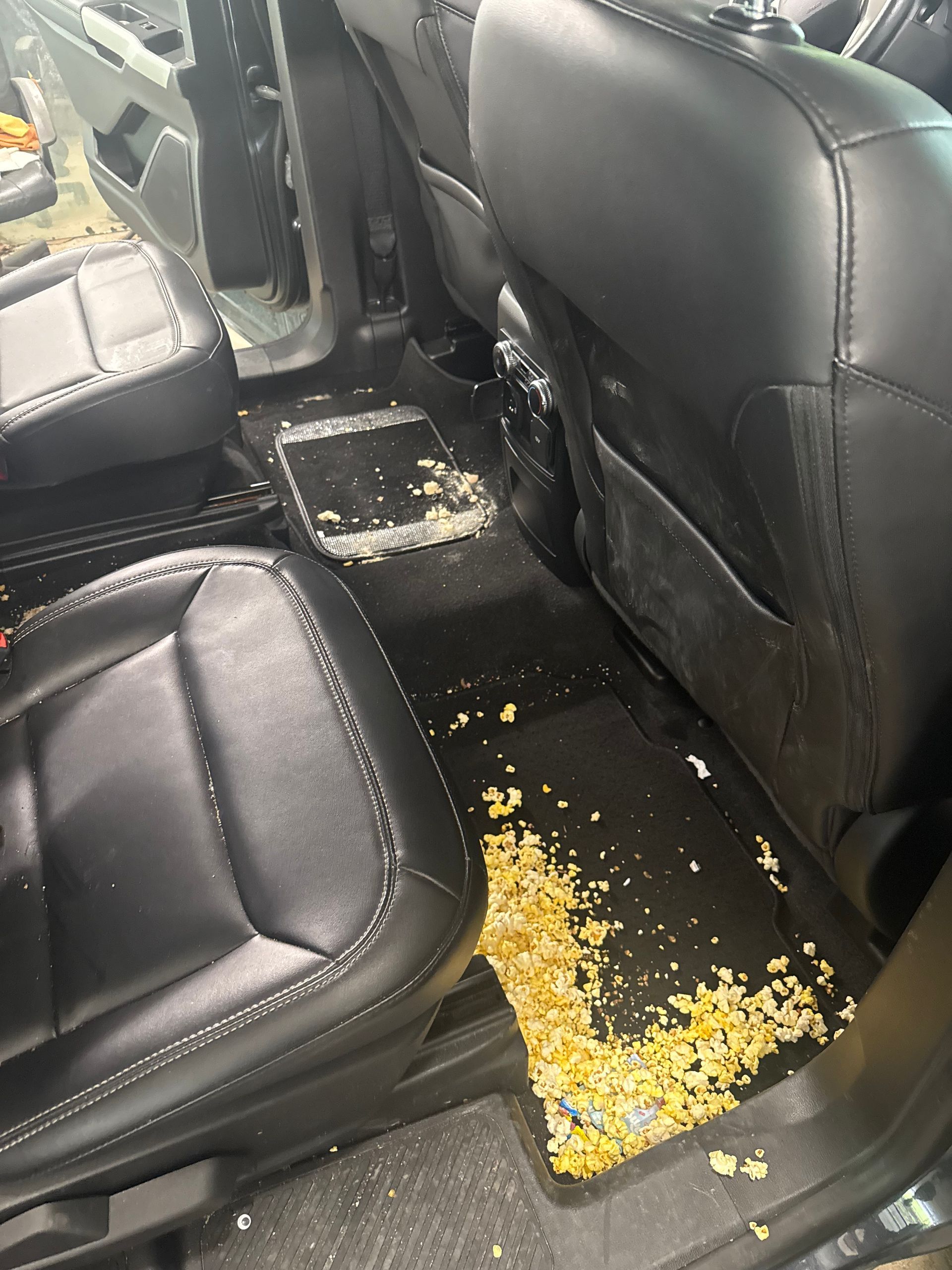 The back seat of a car is dirty and covered in dust.