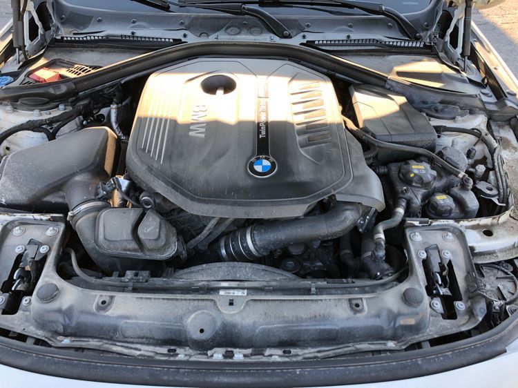 A close up of a dirty car engine with the hood open.