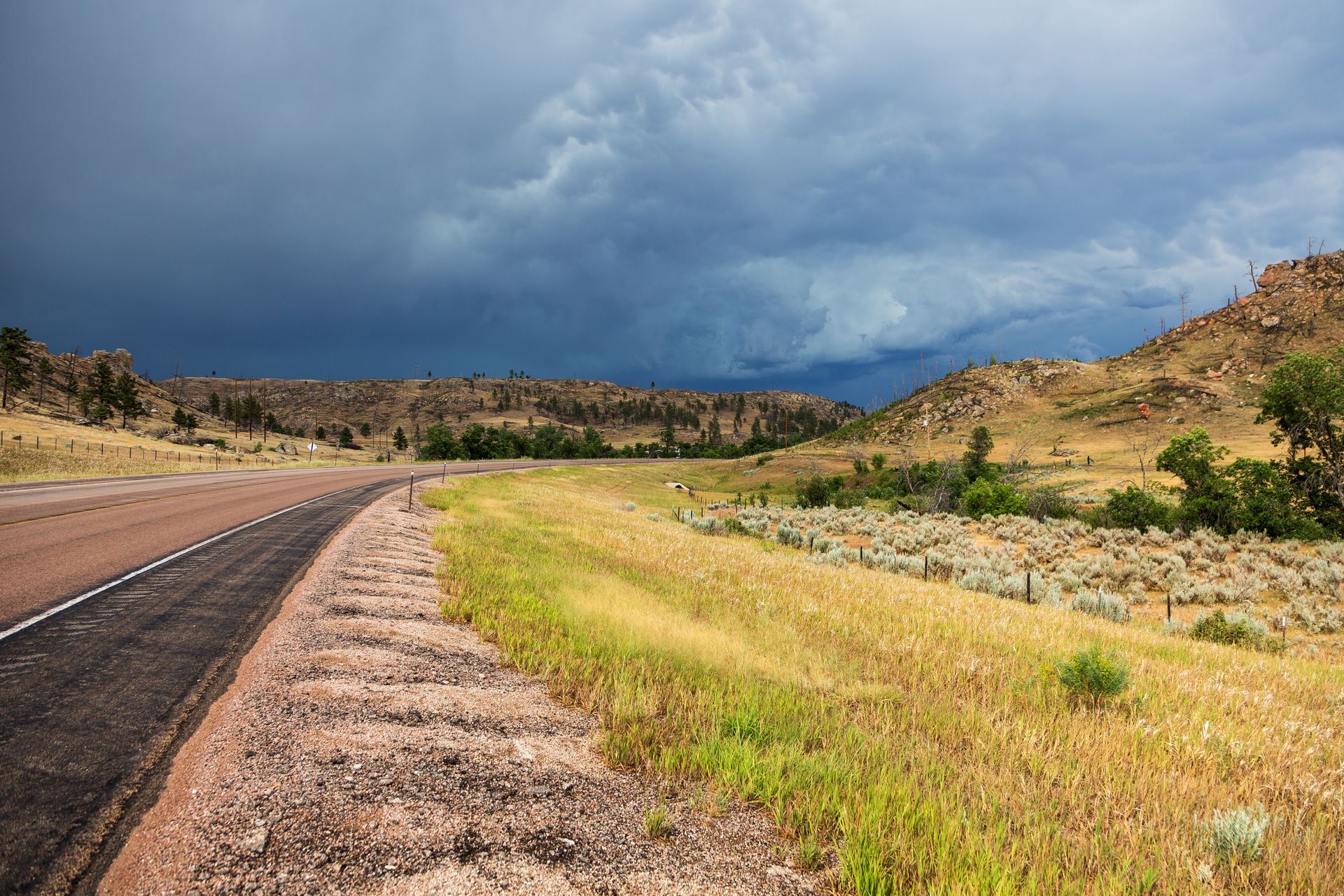 A road in the middle of a field with a cloudy sky in the background.