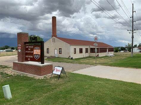 A small white building with a red roof and a sign in front of it.