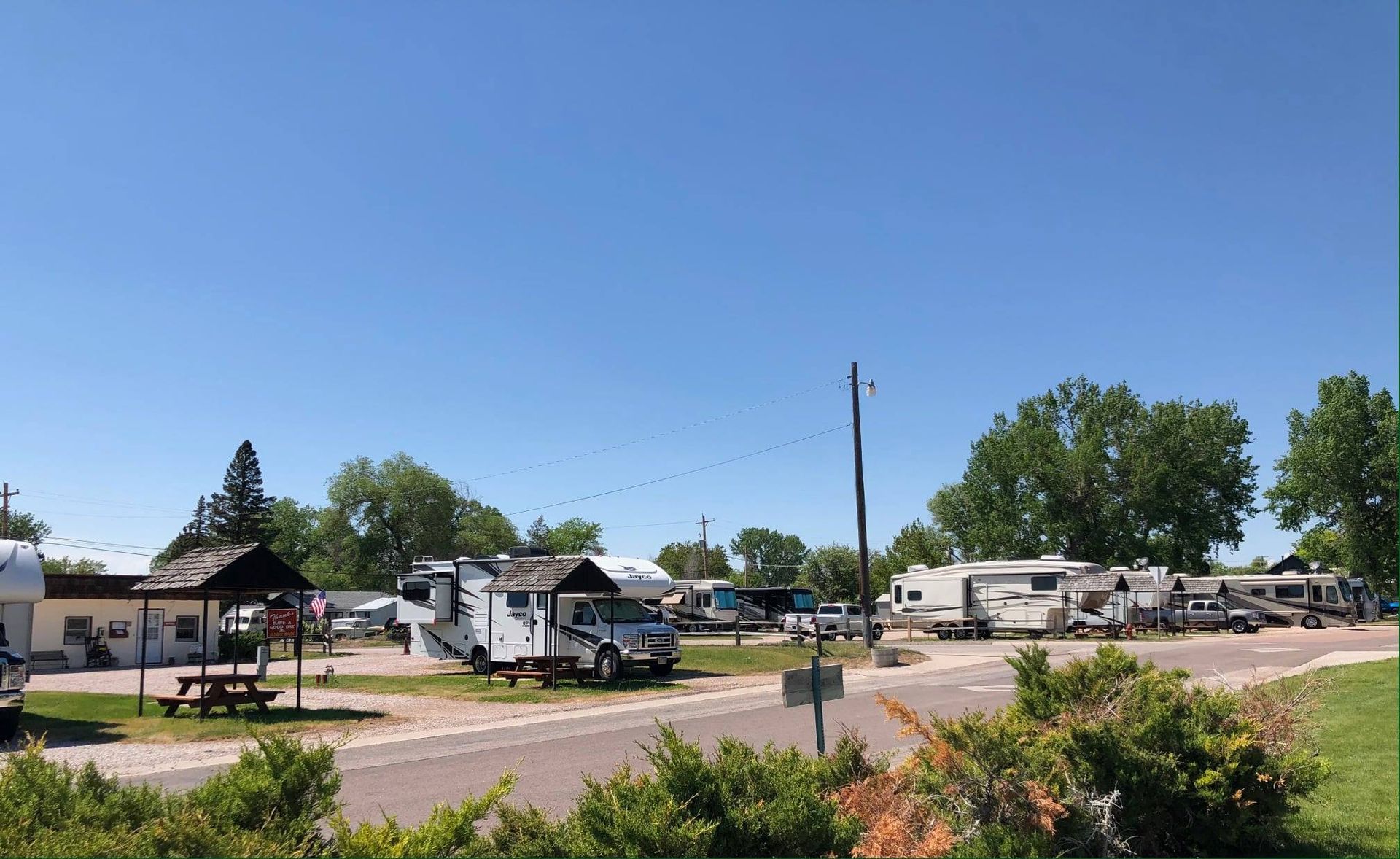 A lot of rvs are parked in a lot on a sunny day.
