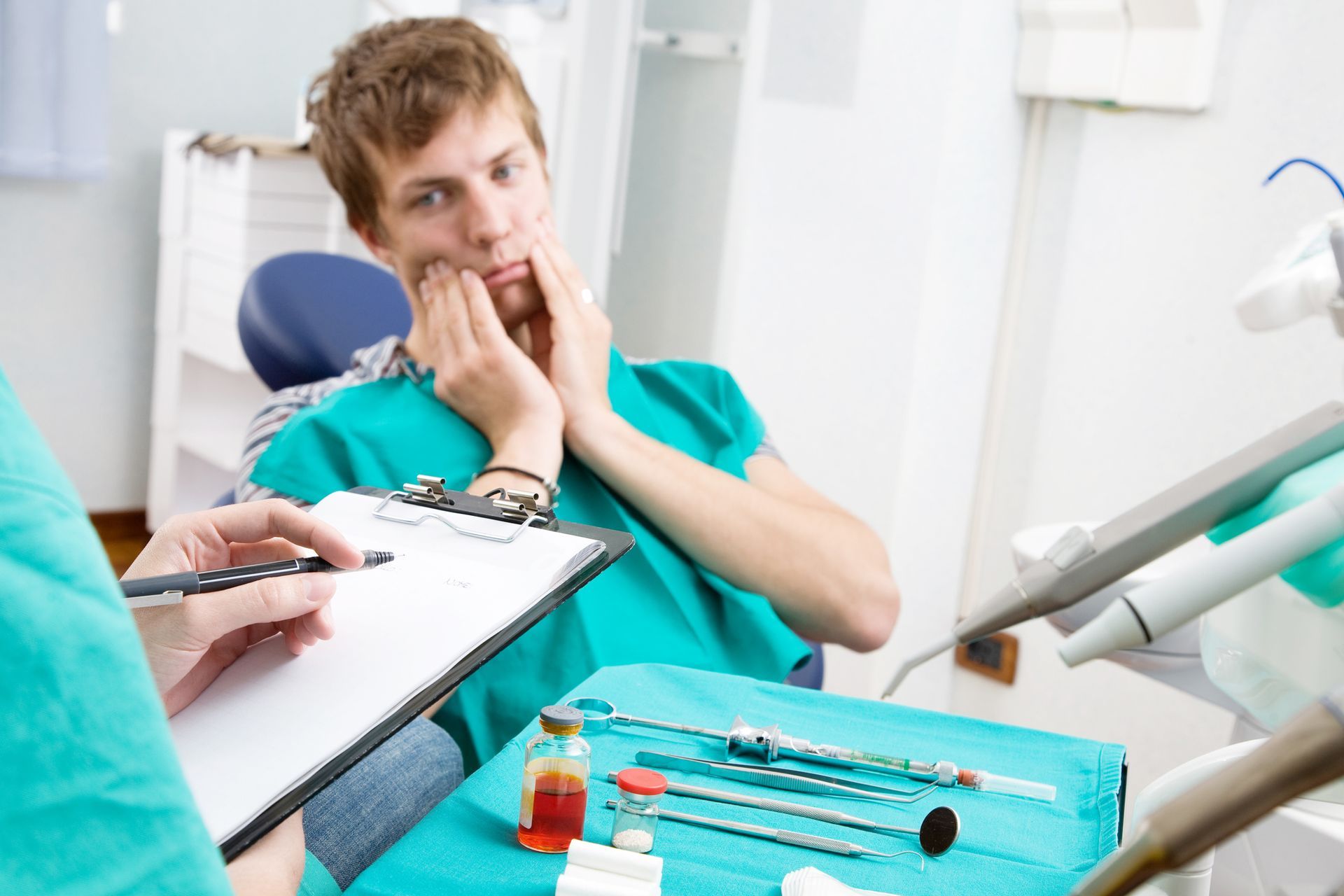 A patient having a toothache at an emergency dentist's office, while the dentist takes notes.