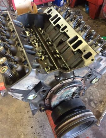 A close up of a car engine being worked on in a garage.