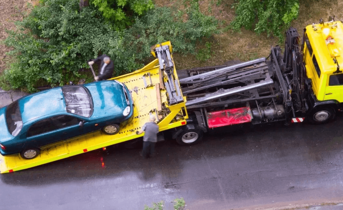 Yellow tow truck servicing a car with a dead battery in New Jersey