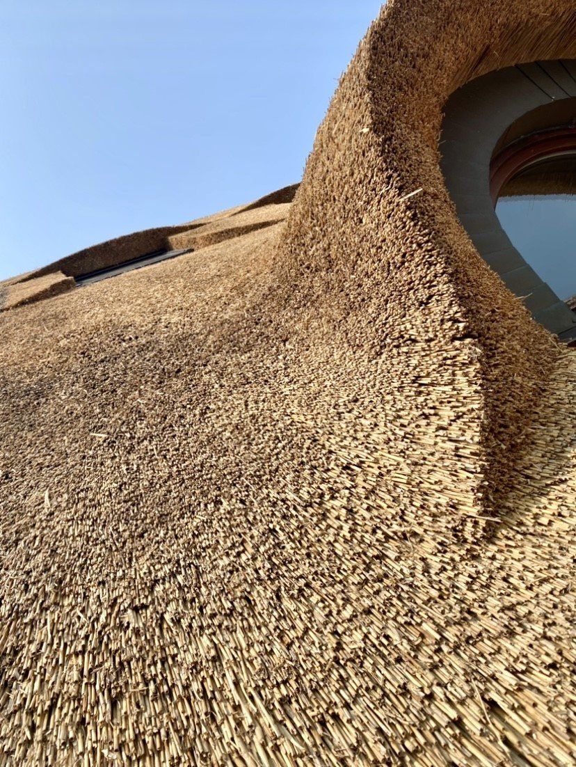 Een close-up van een rieten dak met een rond raam.