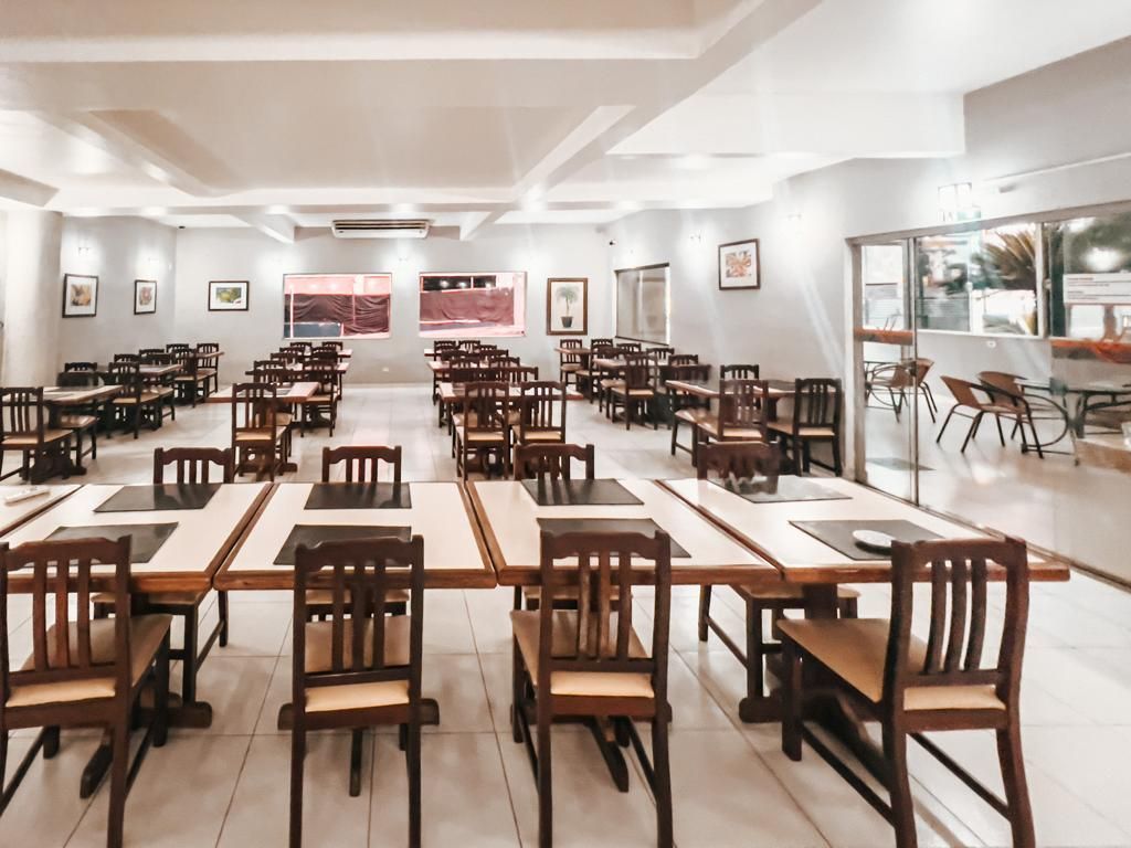 Uma grande sala de jantar com mesas e cadeiras em um restaurante.