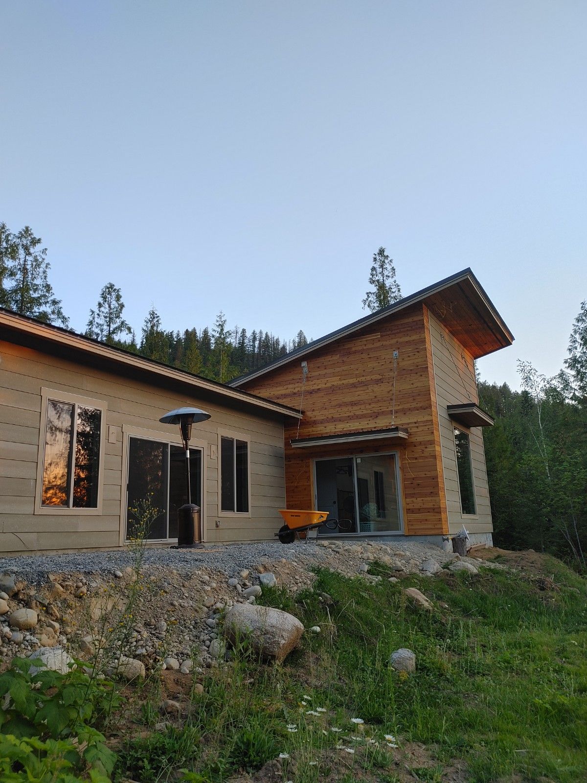 A wooden house with a yellow wheelbarrow in front of it