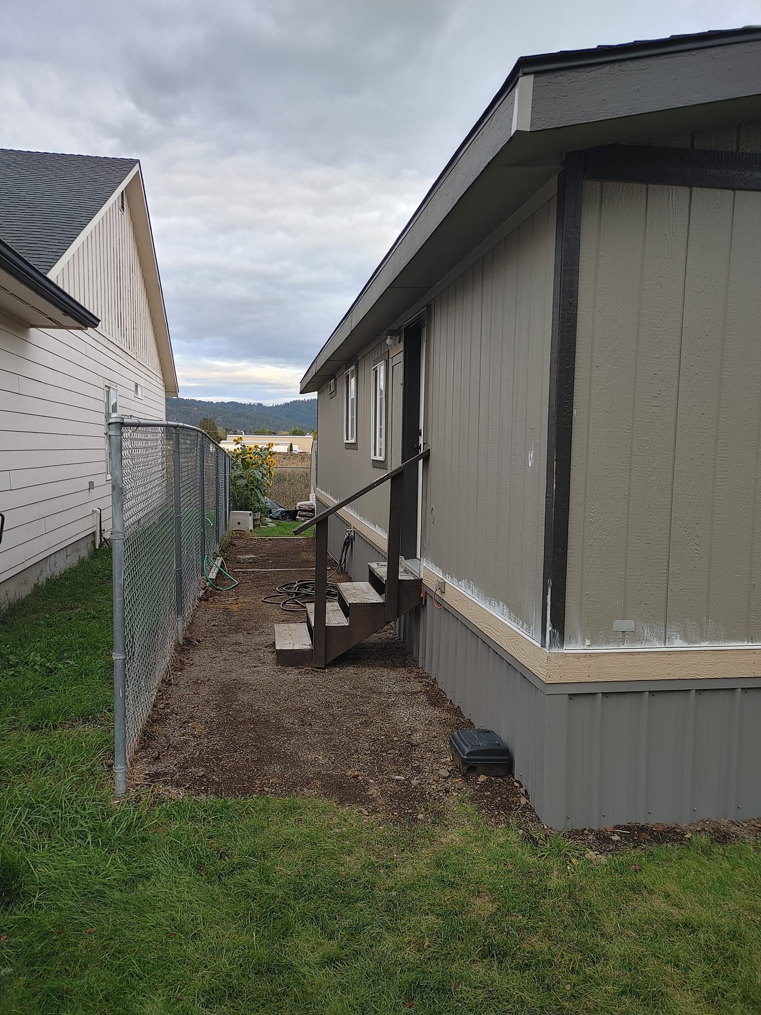 A mobile home with stairs and a chain link fence in the backyard.