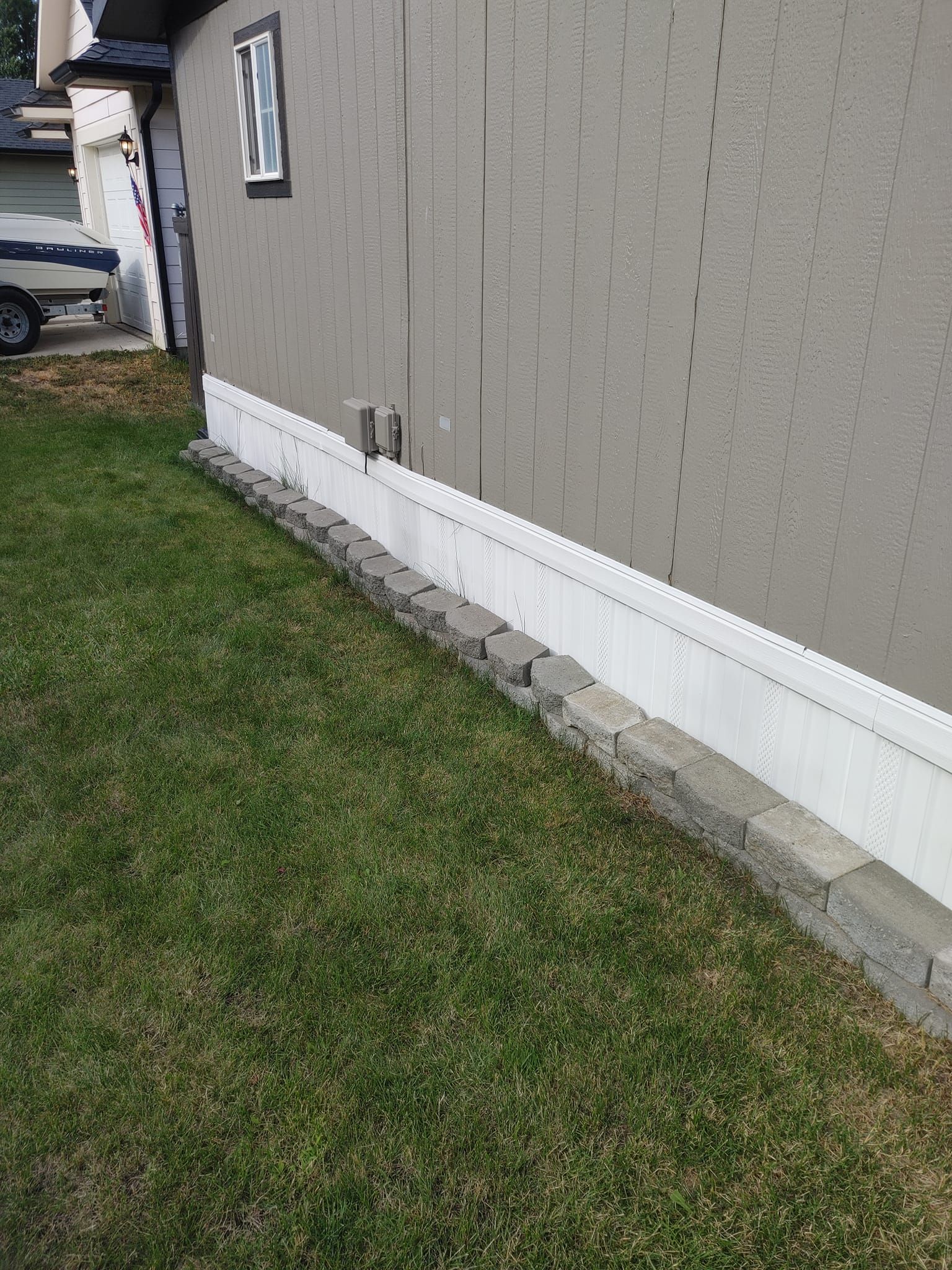 A house with a white trim on the side of it is sitting on top of a lush green lawn.