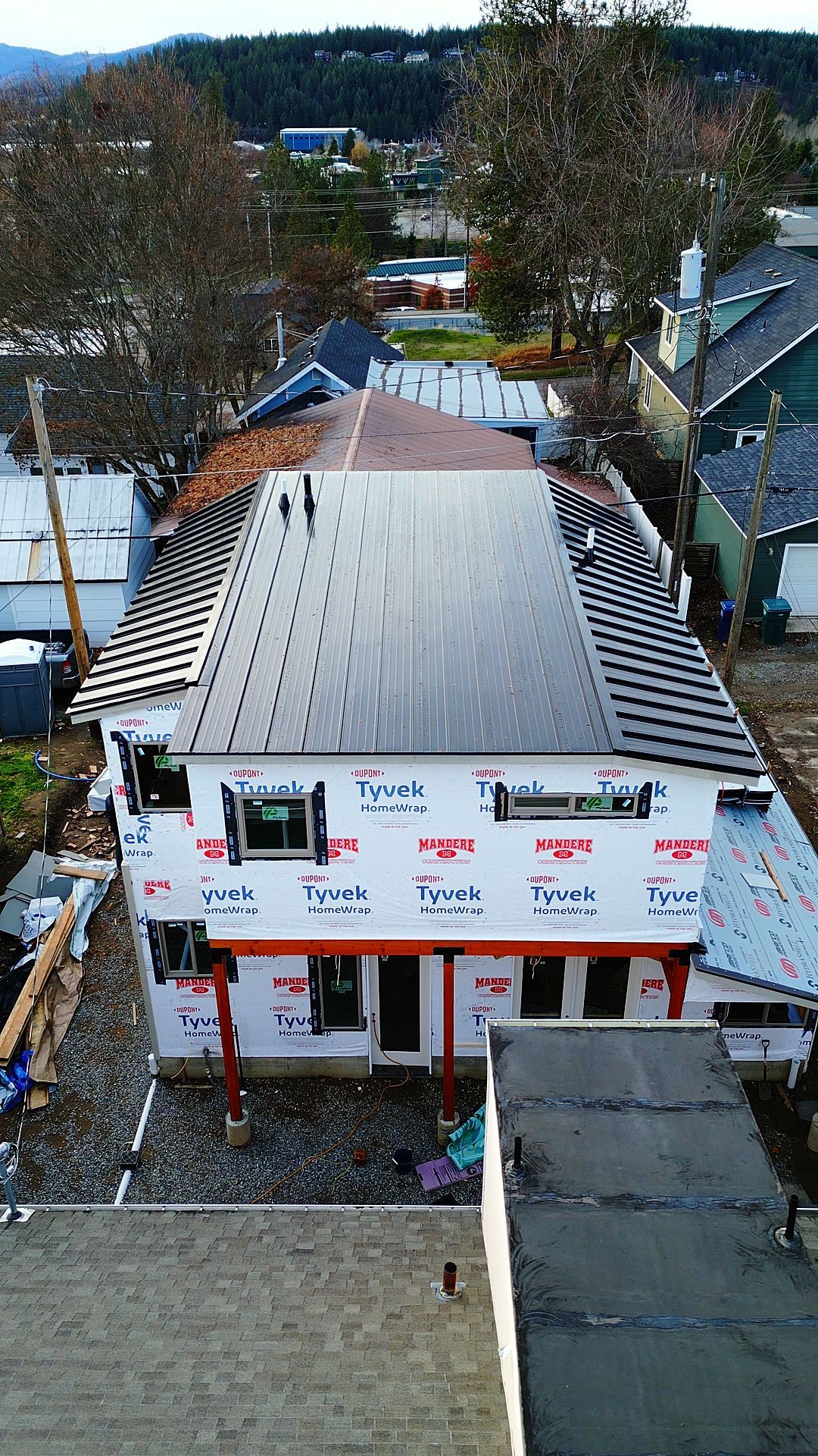 Building under construction; exterior view from above, solar panels on roof, Tyvek wrap on walls.