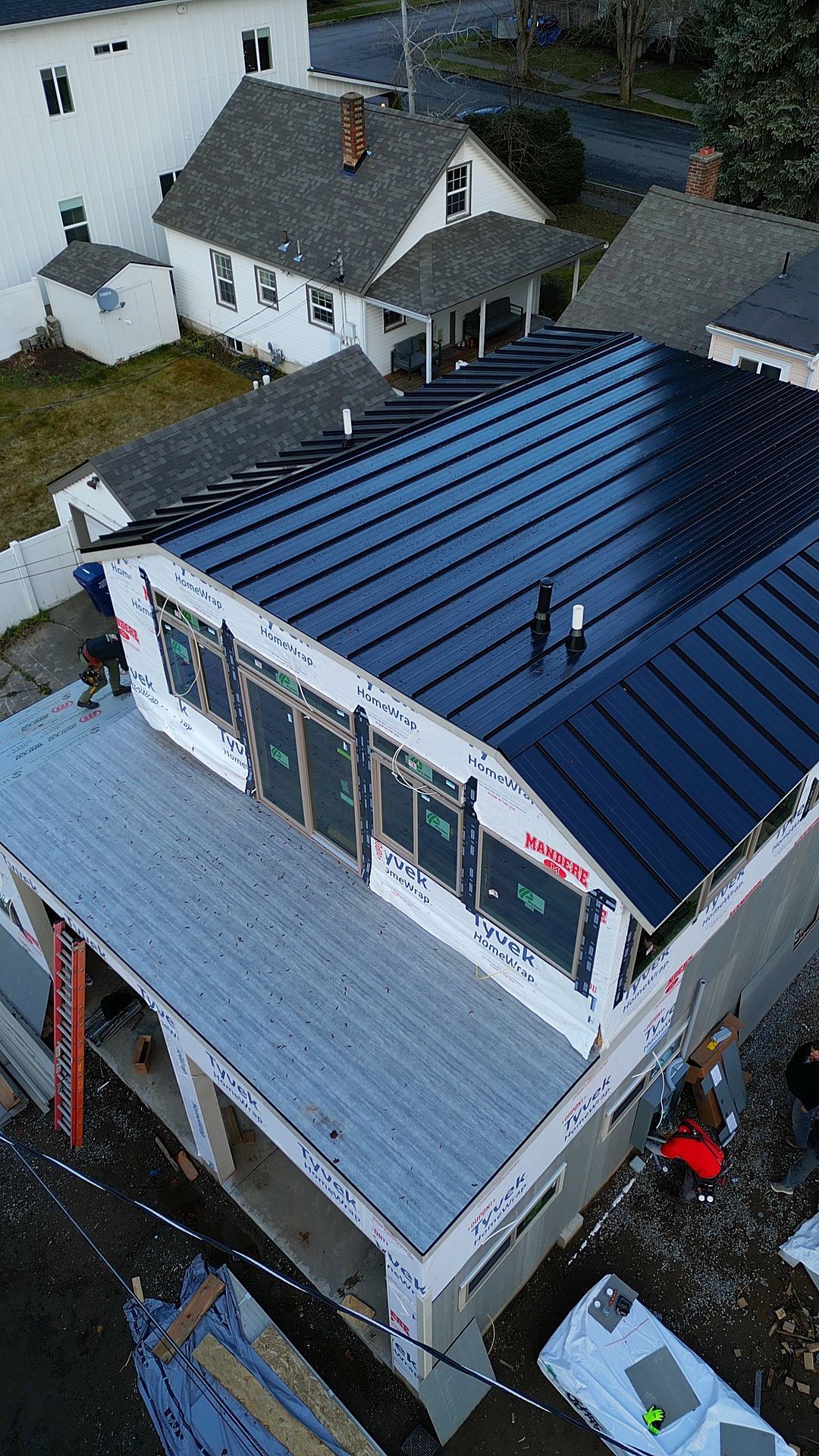 Construction site with a partially built house and black metal roof.