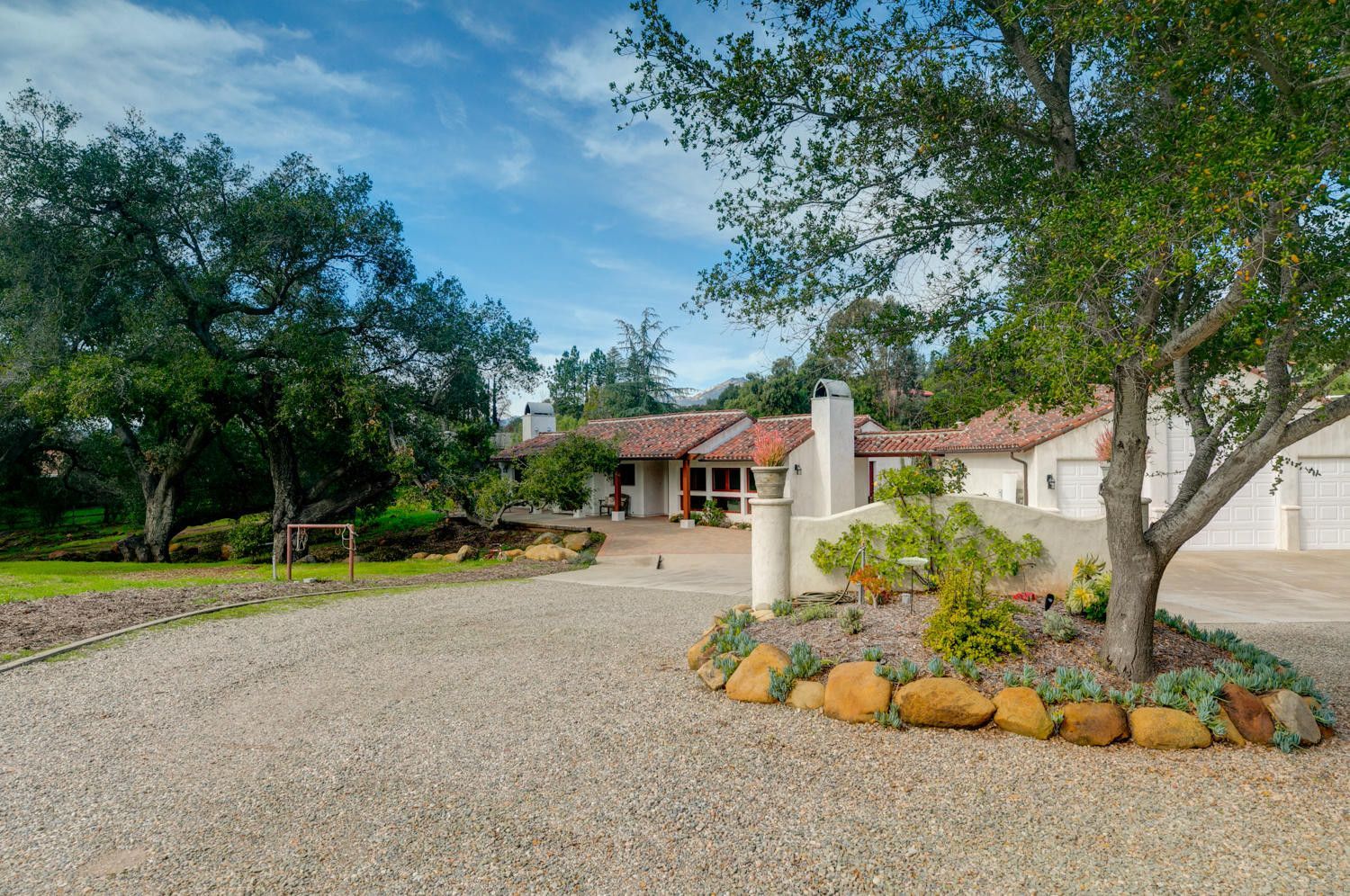 A house with a gravel driveway and trees in front of it