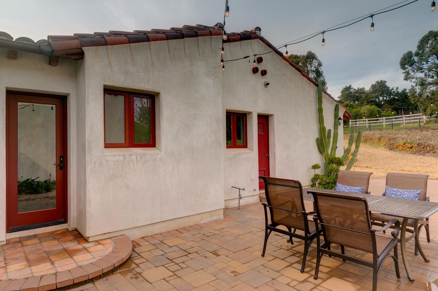 A patio with a table and chairs in front of a white house.