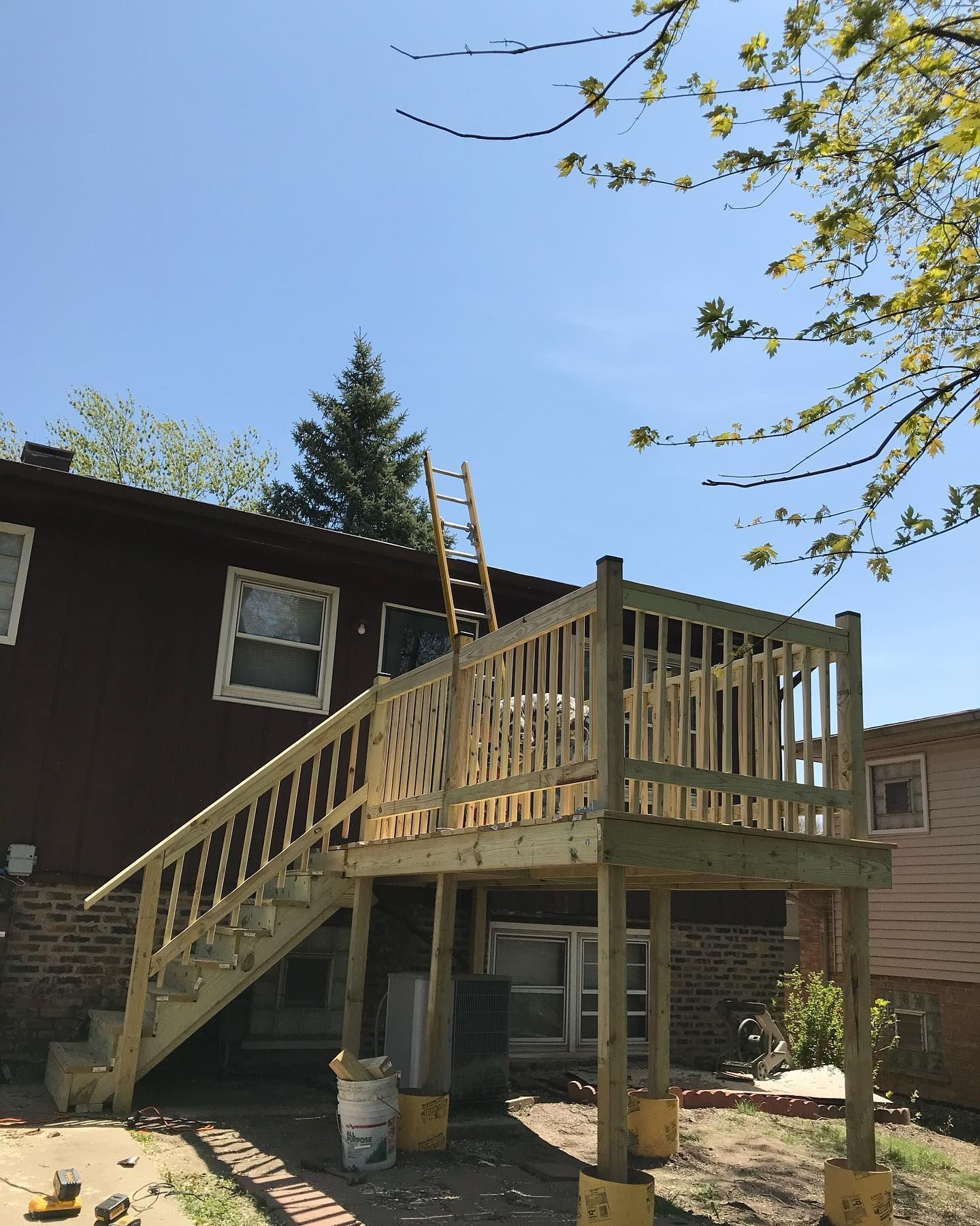 A wooden deck is being built in the backyard of a house