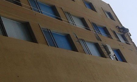 un uomo su una facciata di una casa appeso a delle corde