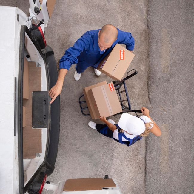 a man and a woman are loading boxes into a white van