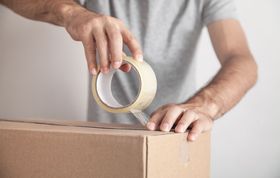 a man is taping a cardboard box with clear tape