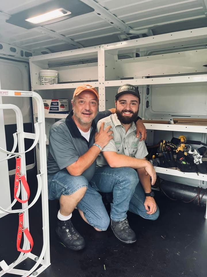 Two men are posing for a picture in the back of a van.