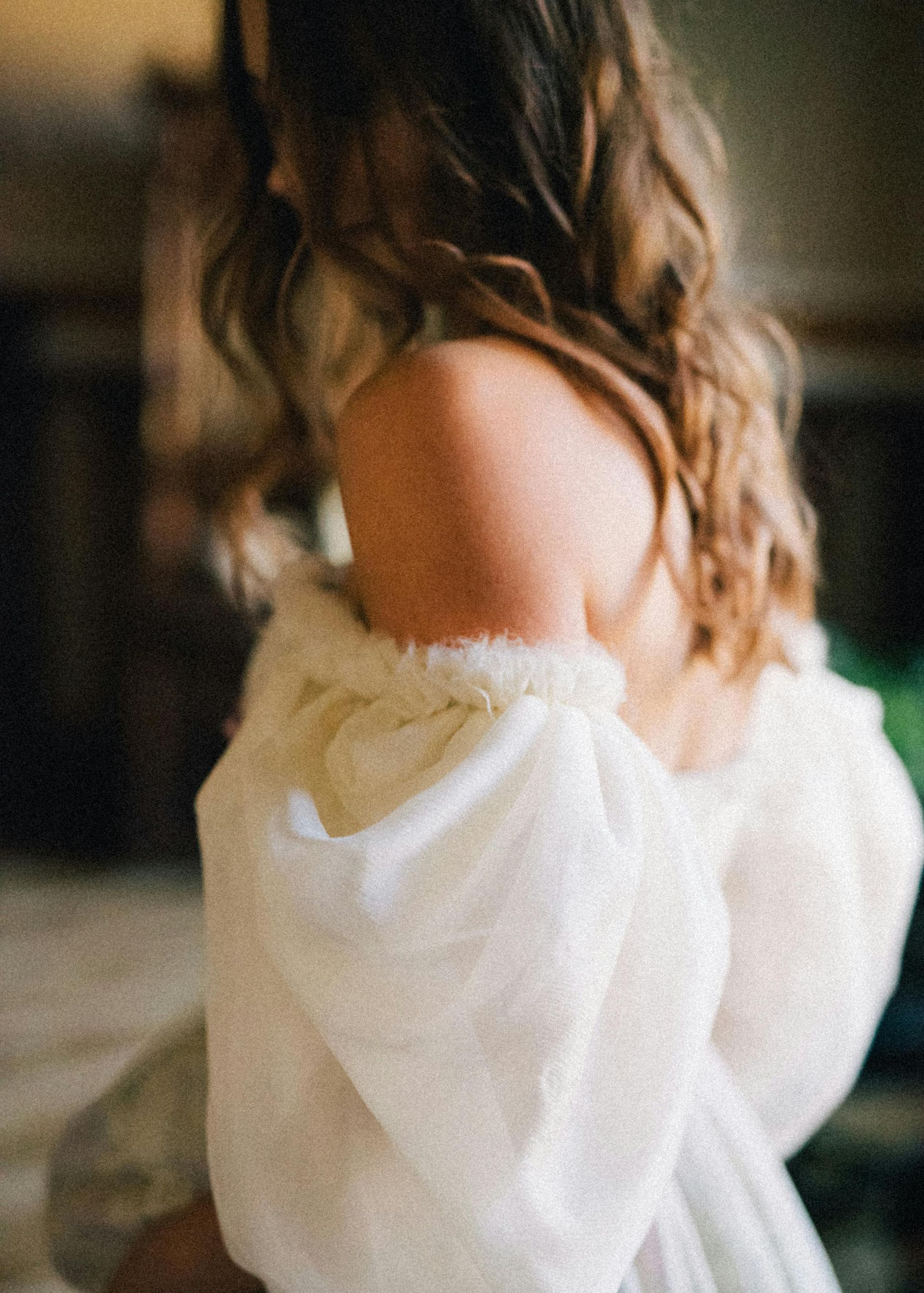 The back of a woman wearing a white dress with puffed sleeves.