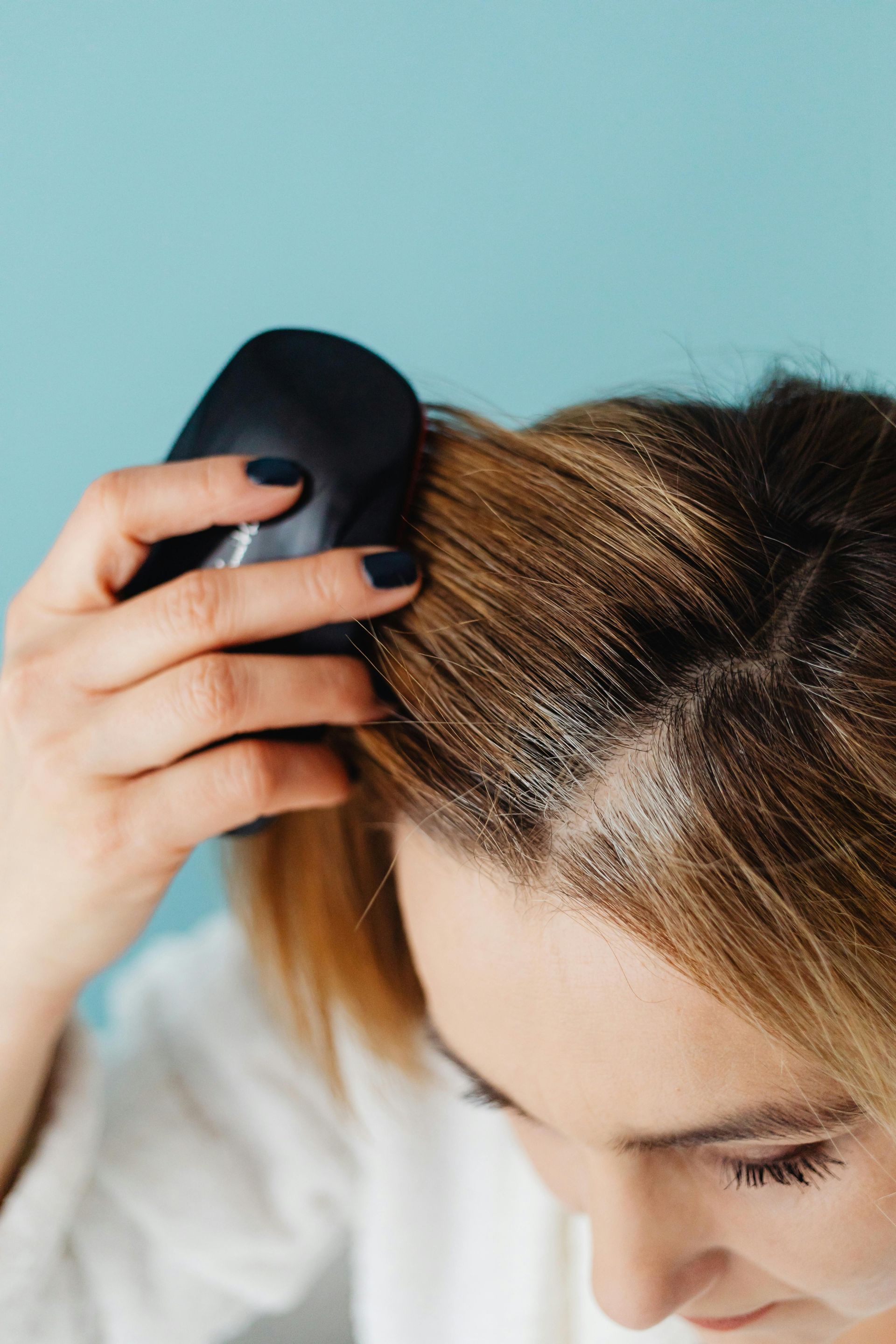 A woman is brushing her hair with a black brush.
