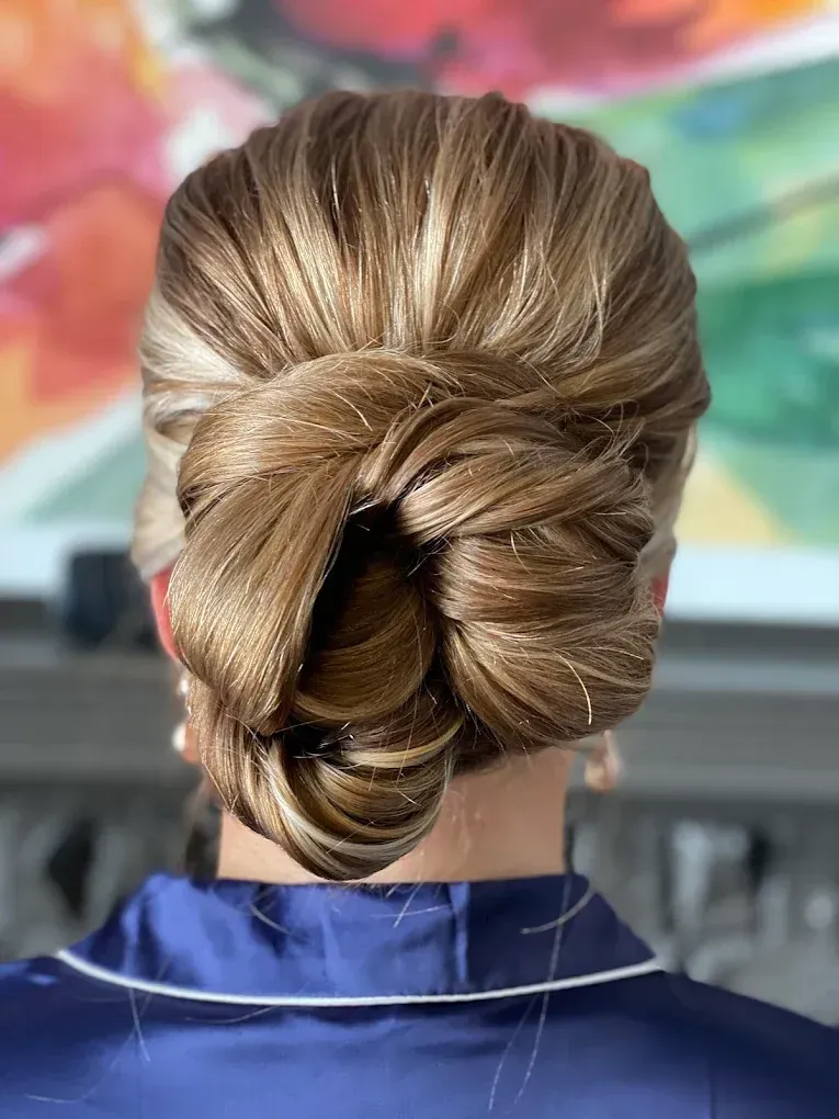 A woman is wearing a blue robe and has her hair in a bun.