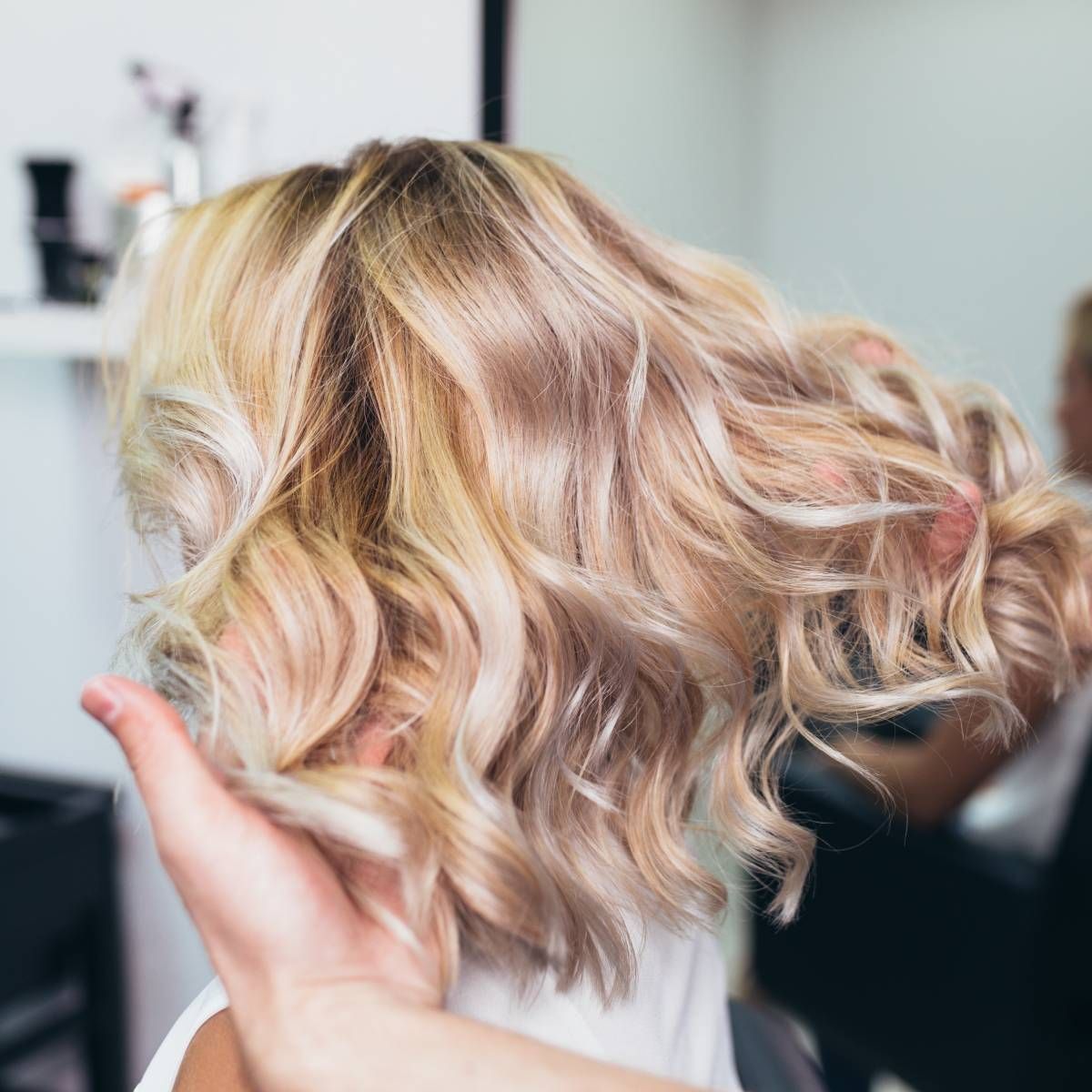 A woman is getting her hair done by a hairdresser in a salon.