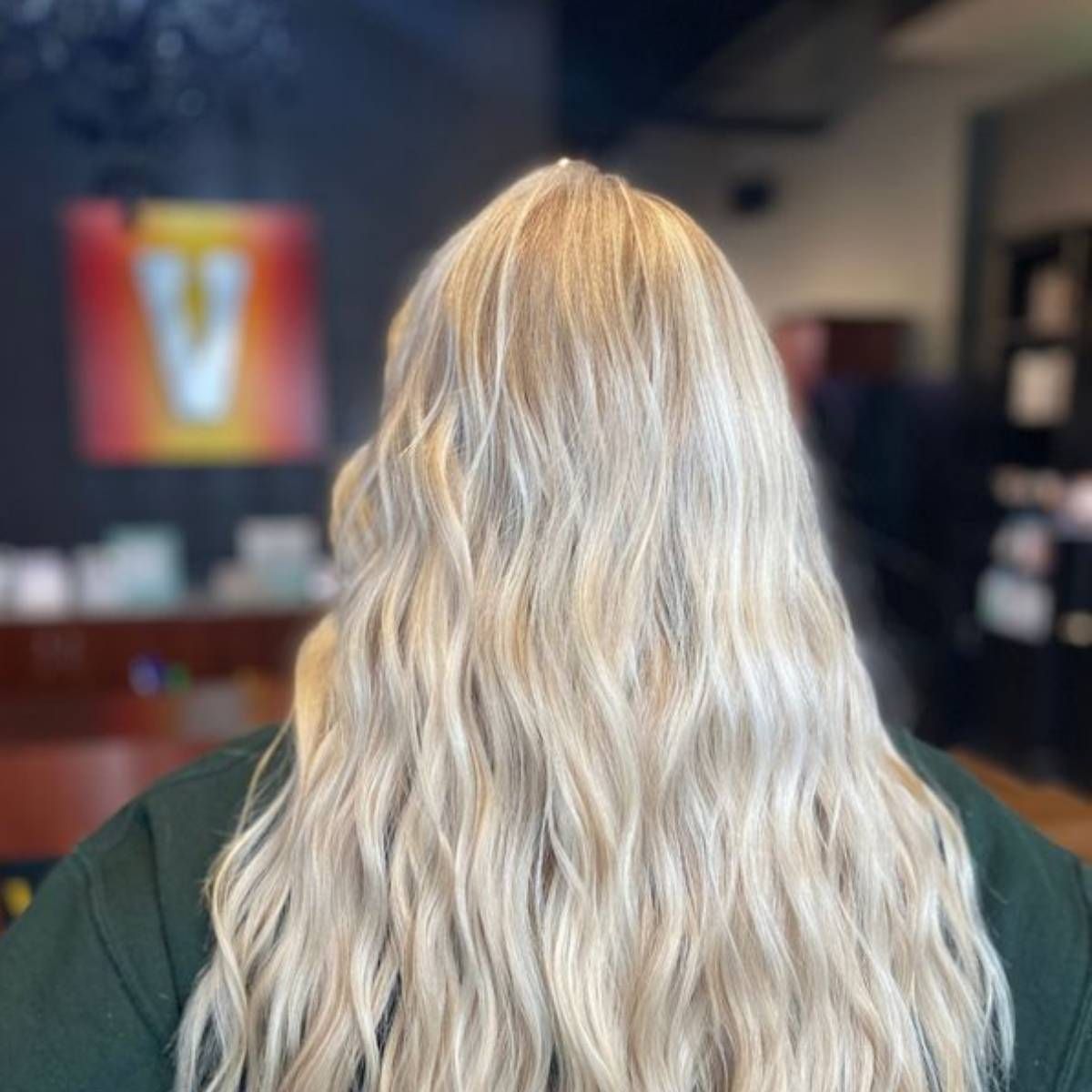 A woman with long blonde hair is wearing a green shirt.