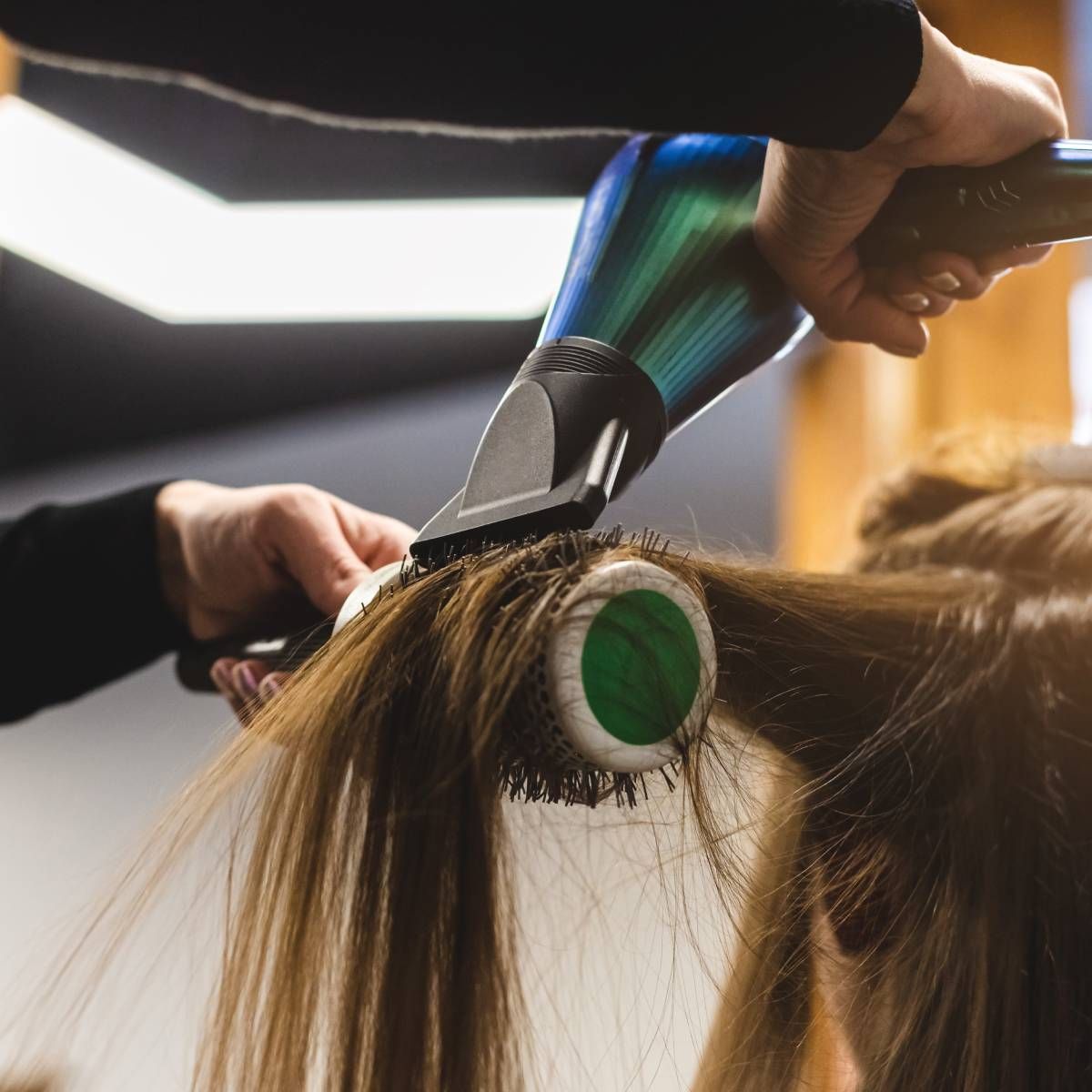 A woman getting her hair blow dried with a green brush