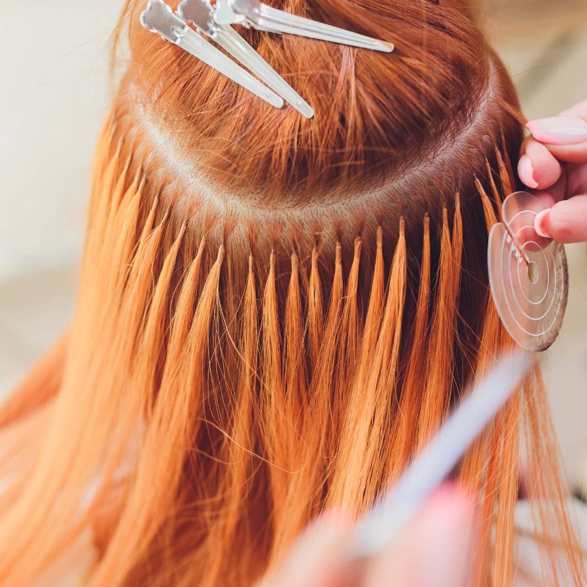 A woman with red hair is getting her hair extensions done