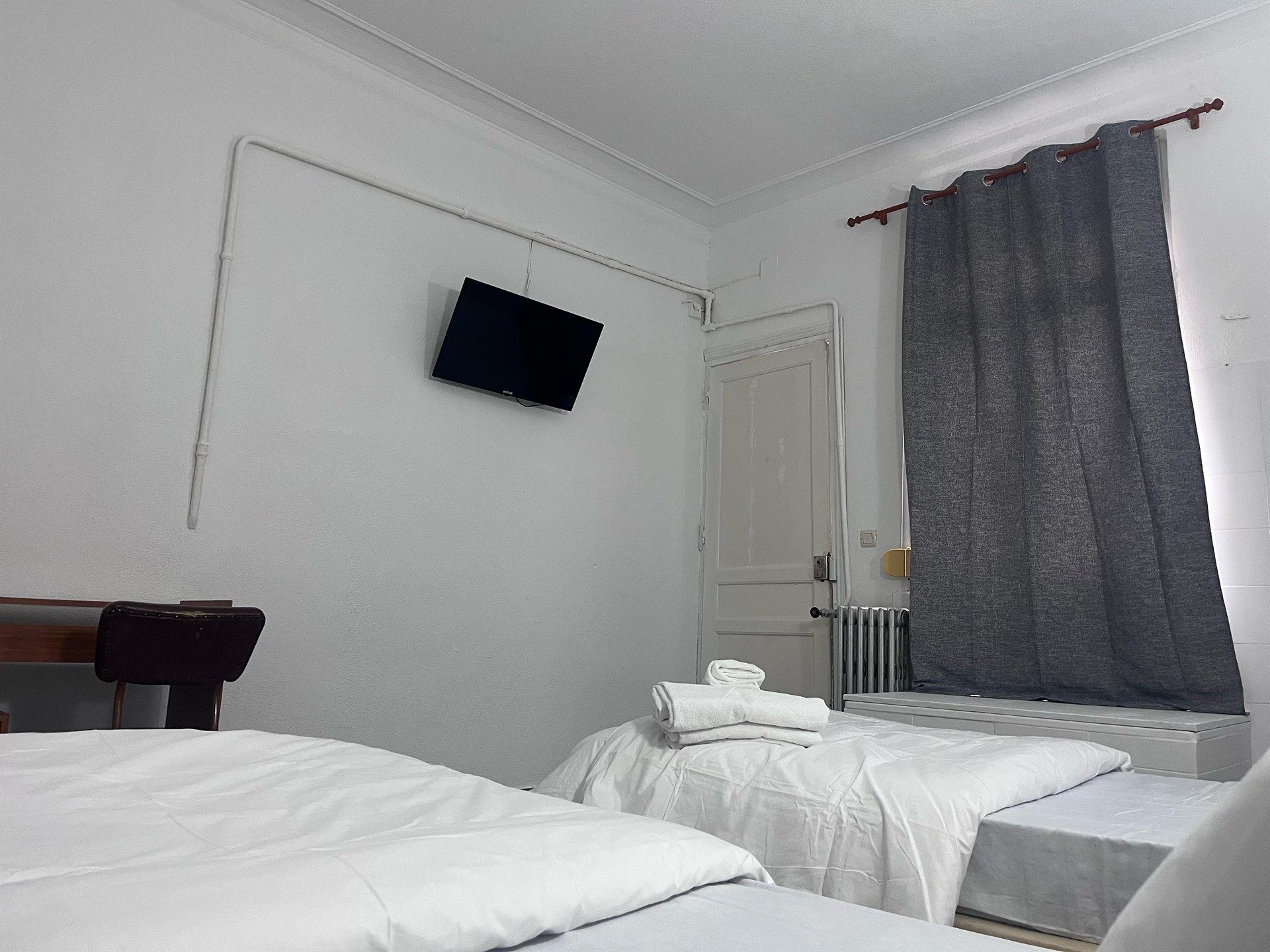 A bedroom with two beds and a television on the wall.