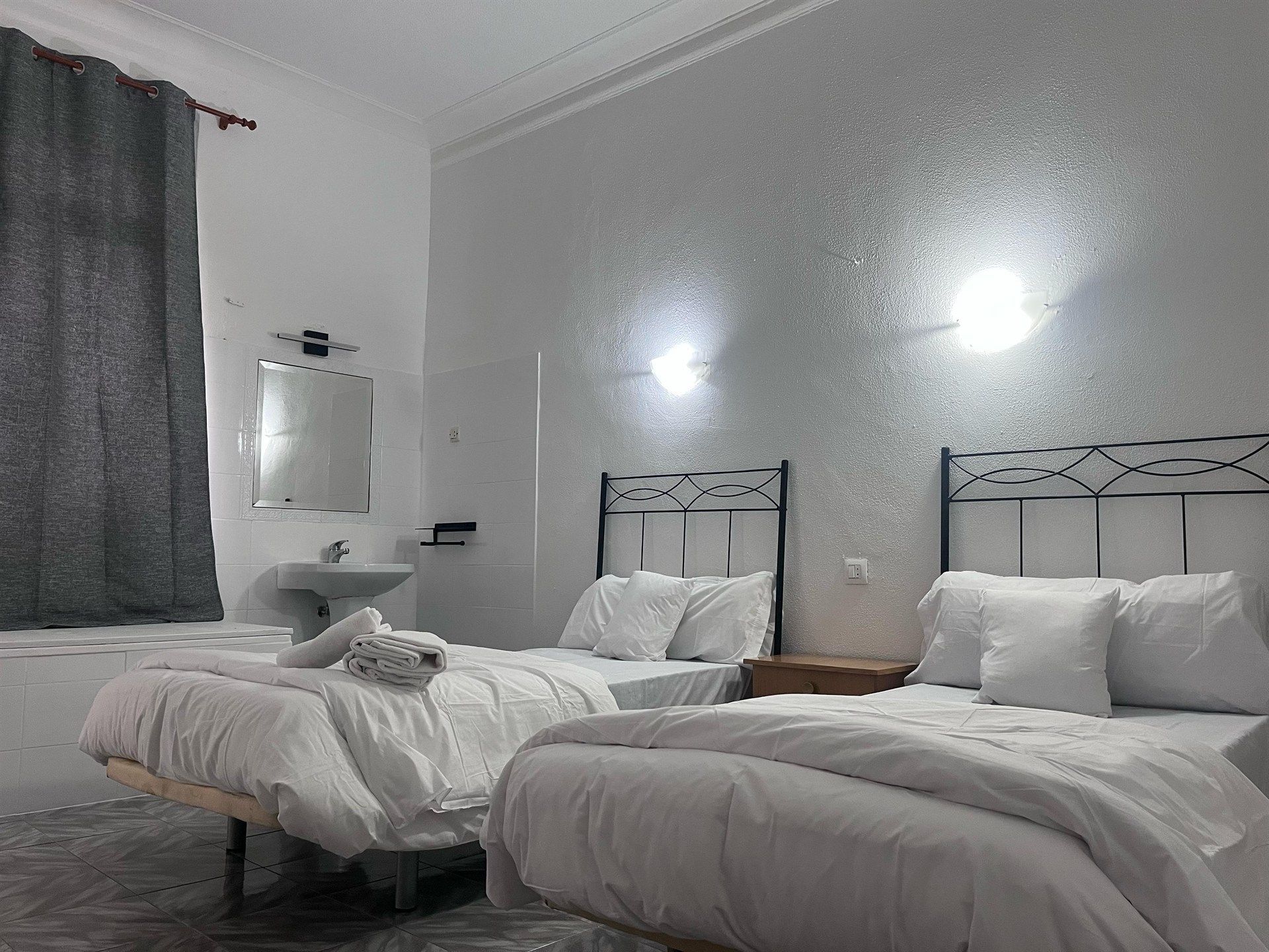 A hotel room with two beds , a sink and a mirror.