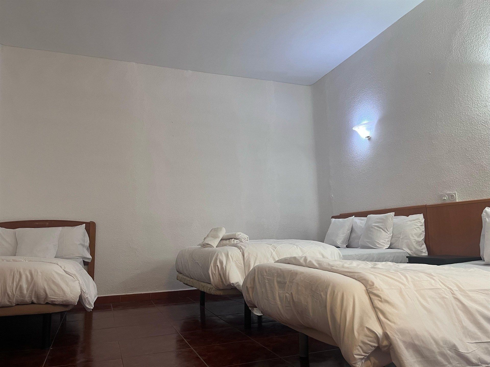 A hotel room with three beds and a couch.