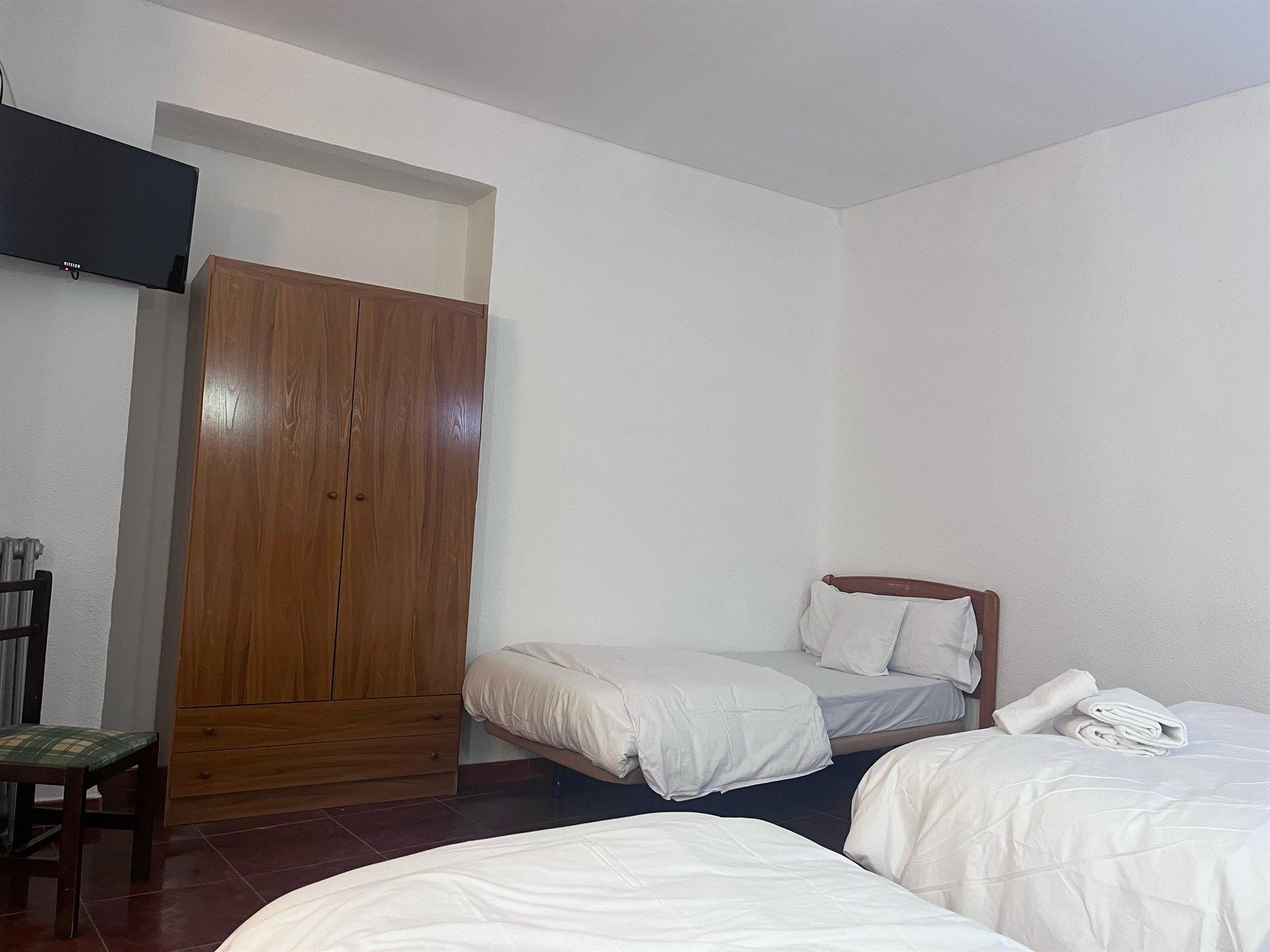 A bedroom with two beds , a dresser and a television.