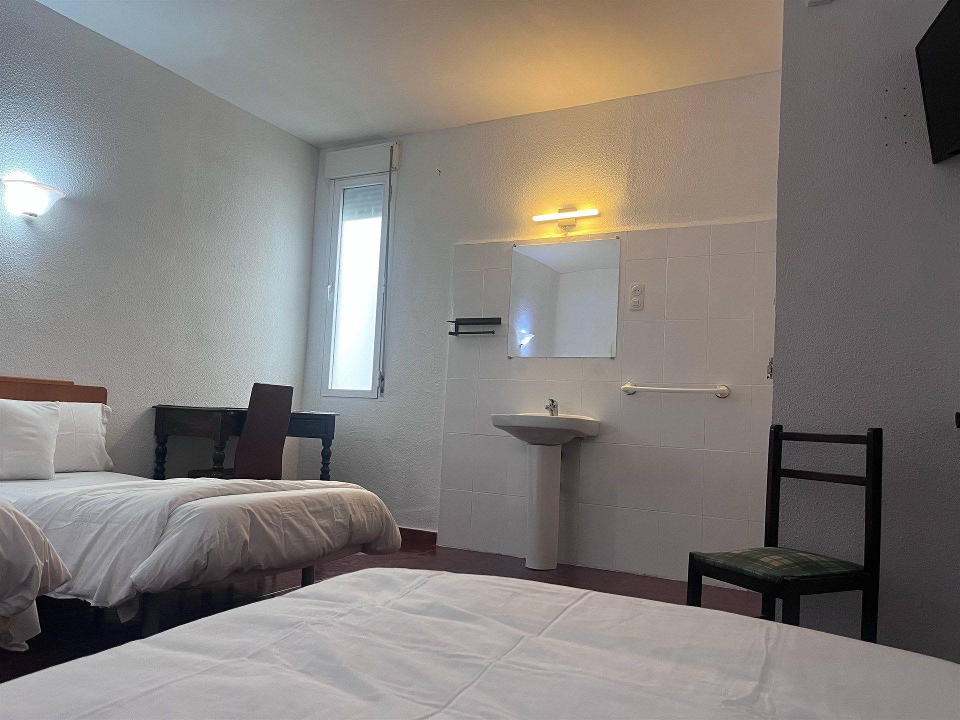 A hotel room with two beds and a sink.