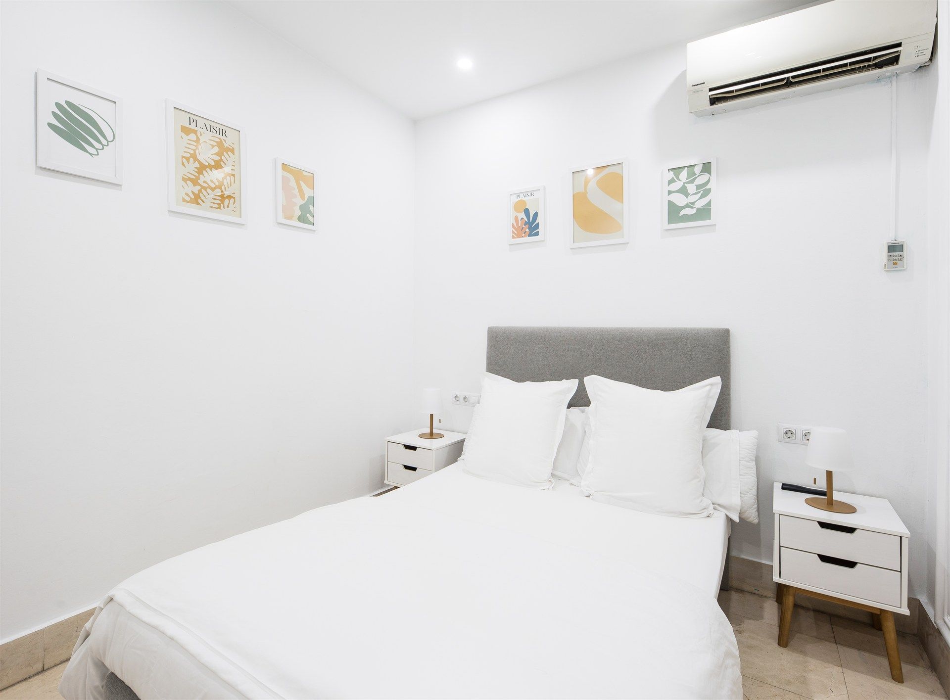 A bedroom with a bed , nightstands , and a air conditioner.