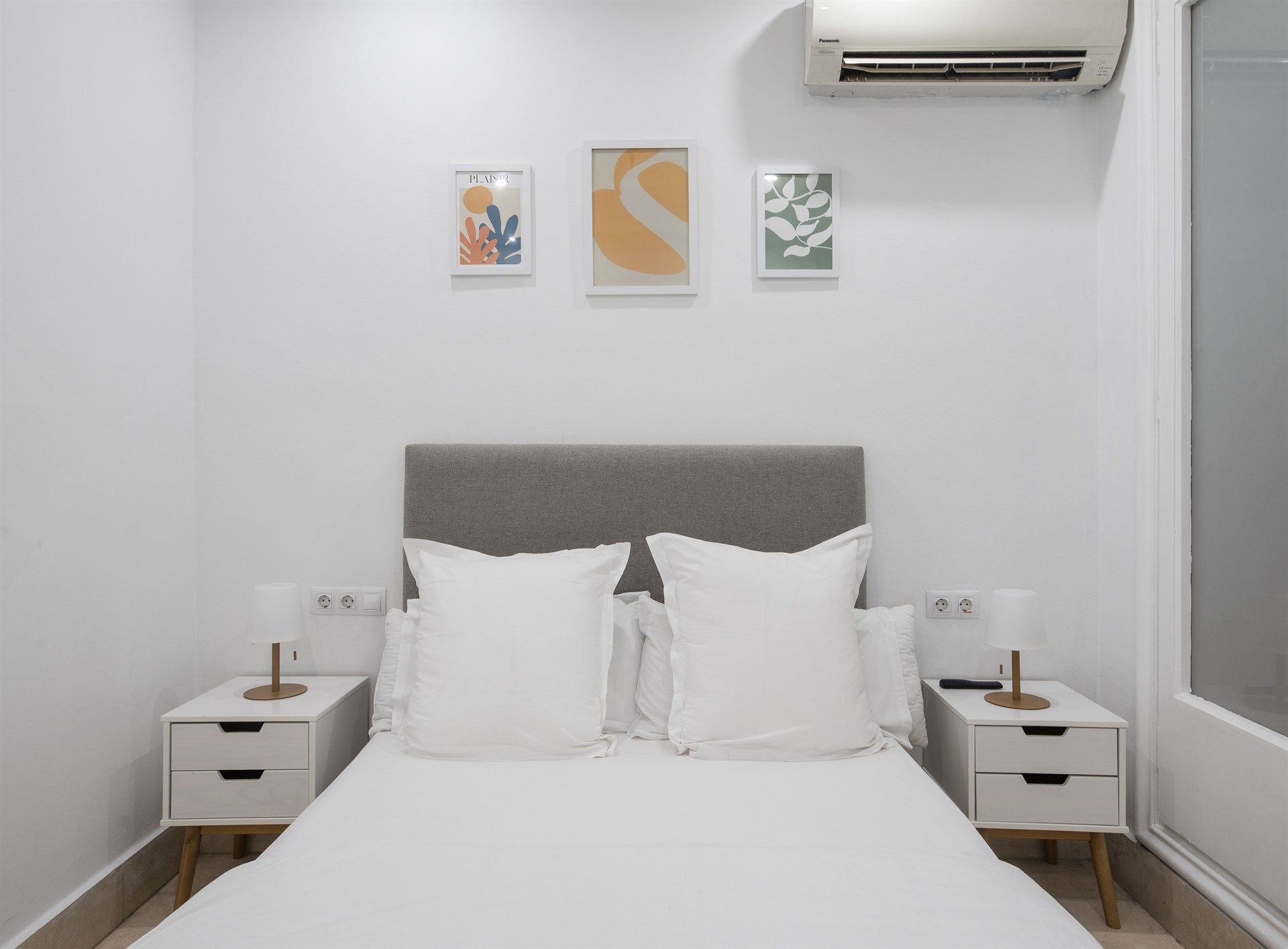 A bedroom with a bed , nightstands , and a air conditioner.