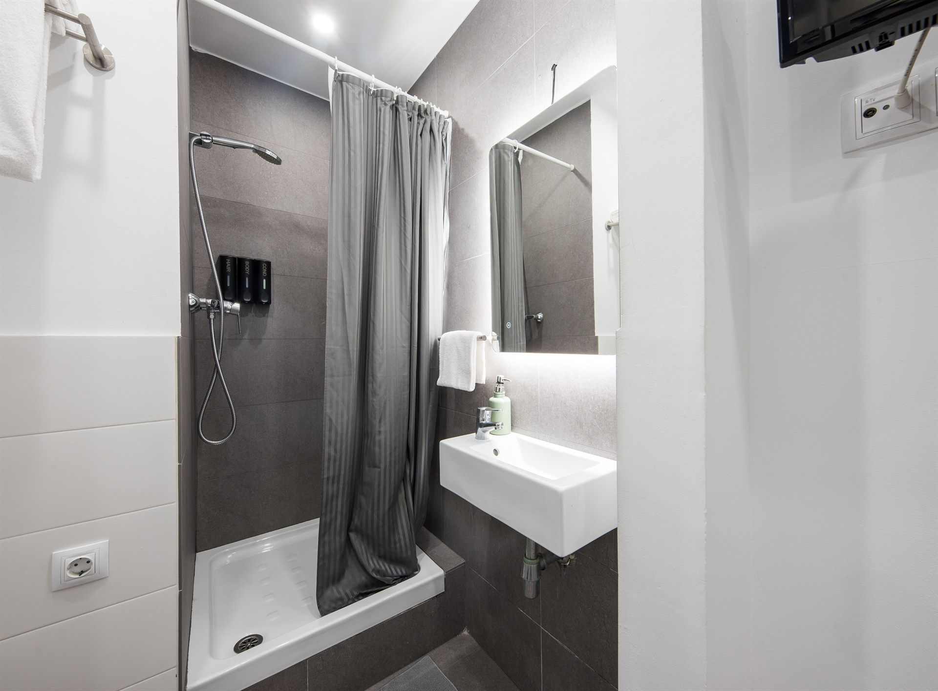 A bathroom with a shower , sink and mirror.