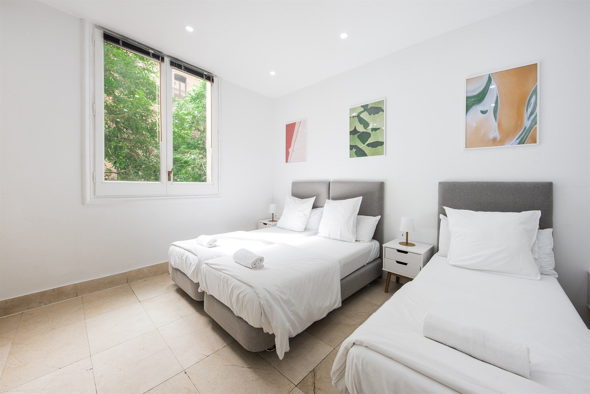 A bedroom with two beds and a window.