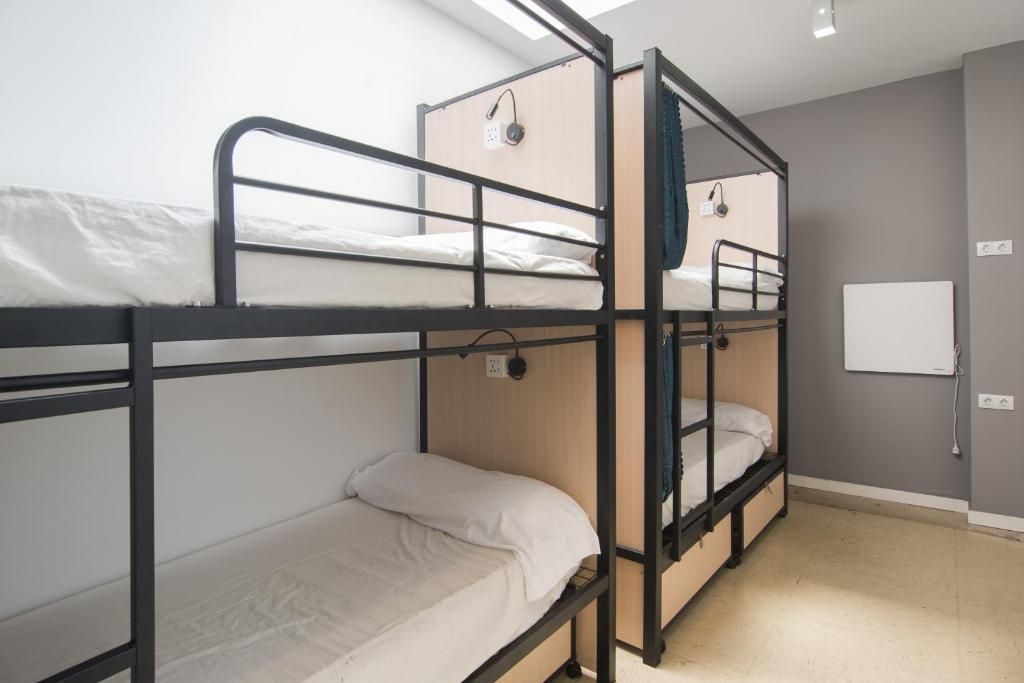 A room with four bunk beds and a white board on the wall.