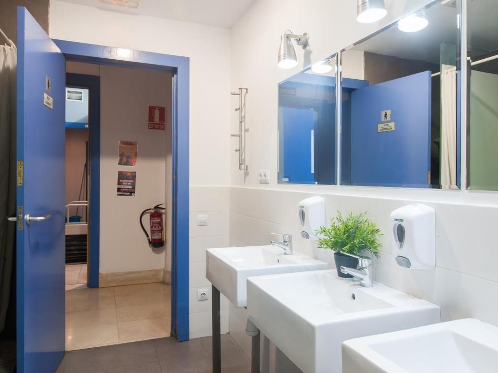 A bathroom with two sinks , a mirror and a fire extinguisher.