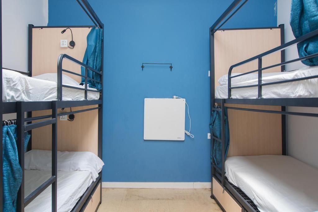 A room with four bunk beds and a blue wall.