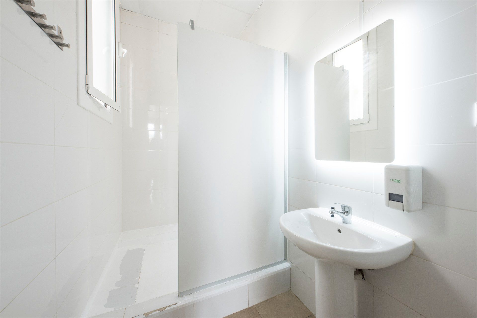 A bathroom with a sink , mirror and shower.