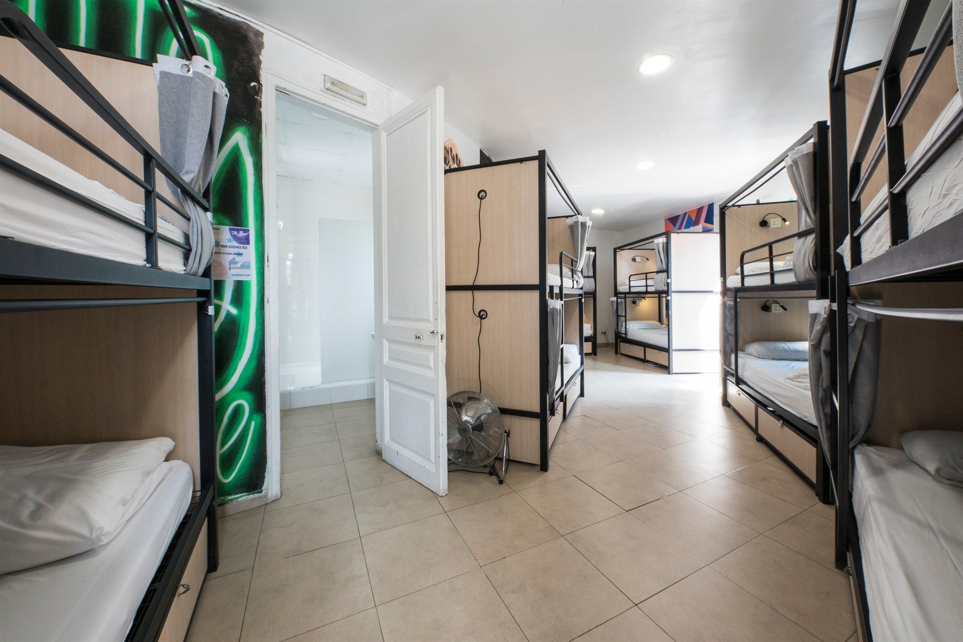 A room with bunk beds and a neon sign on the wall.